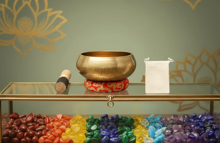 Bronze singing bowl with red base and wooden mallet on a white background